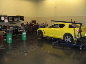 front wheels off, hood off, engine and transmission on barrels